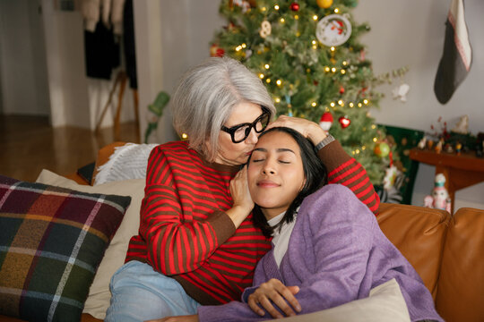 Mature woman kisses young woman on the forehead at Christmas