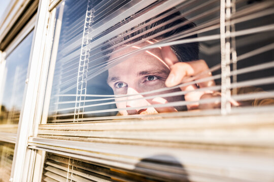 Man peeking through sunblind