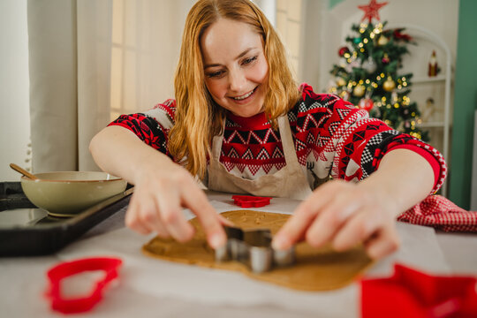 Smiling woman baking gingerbread cookies at home during Christmas