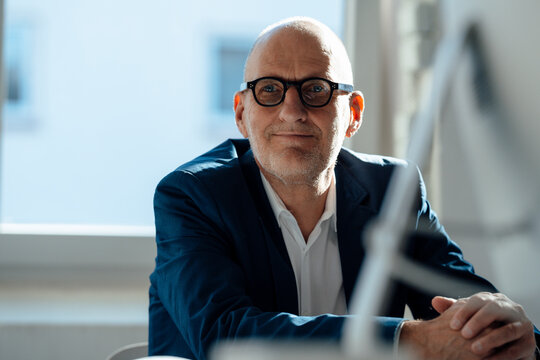 Smiling businessman wearing eyeglasses sitting in office