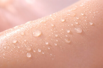Fototapeta premium Closeup of clear water droplets on smooth human skin, highlighting hydration, freshness, and skincare