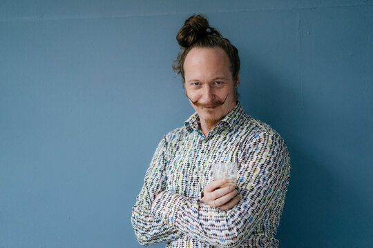 Portrait of man with moustache standing at blue wall