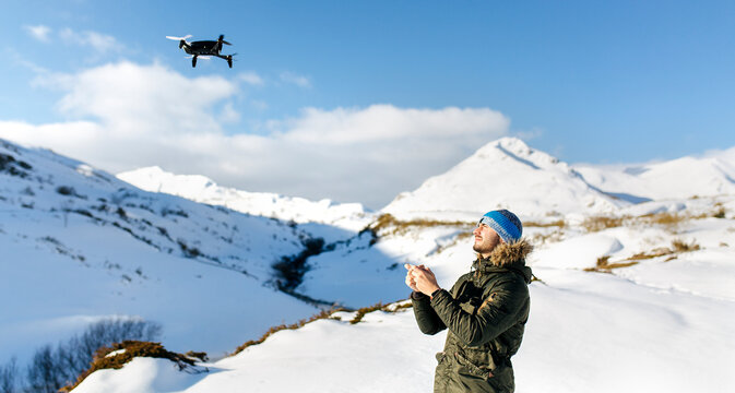 Spain, Asturias, man flying drone in snowy mountains