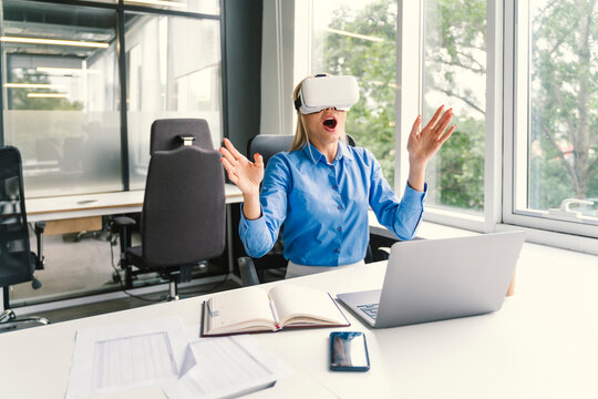 Surprised businesswoman wearing virtual reality headset in office