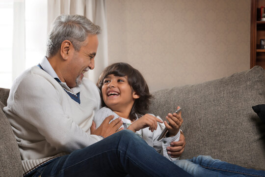 Smiling grandfather and grandson using cell phone