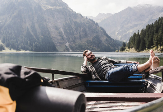 Austria, Tyrol, Alps, relaxed man in boat on mountain lake