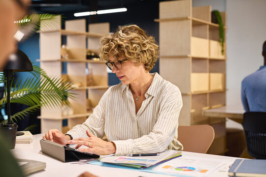 Mature businesswoman using digital tablet at coworking space