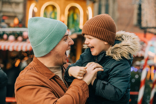 Cheerful father having fun with son at Christmas market