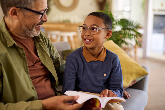 Black cute little boy looking his grandfather while learns to read