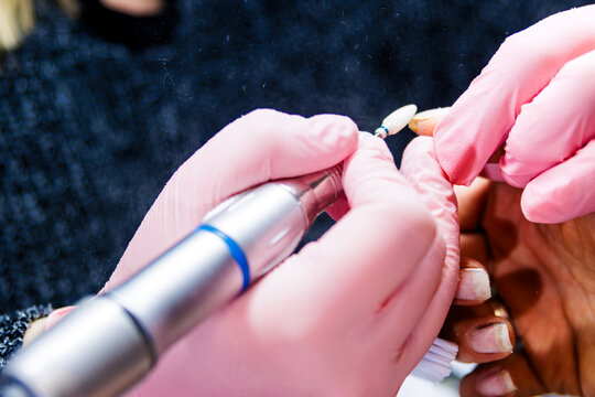 Professional manicurist performing nail hardware treatment at beauty salon