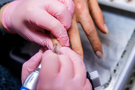 Manicurist working on client's nails using an electric drill in a beauty salon