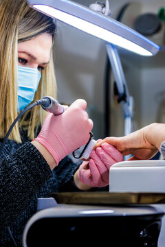 Manicurist wearing mask and gloves providing professional nail care service