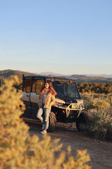 Woman Leaning on Off-Road Vehicle at Sunset © Maria Rasin