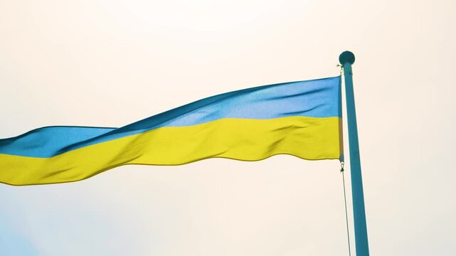 Ukrainian national flag waving proudly from pole against bright sky