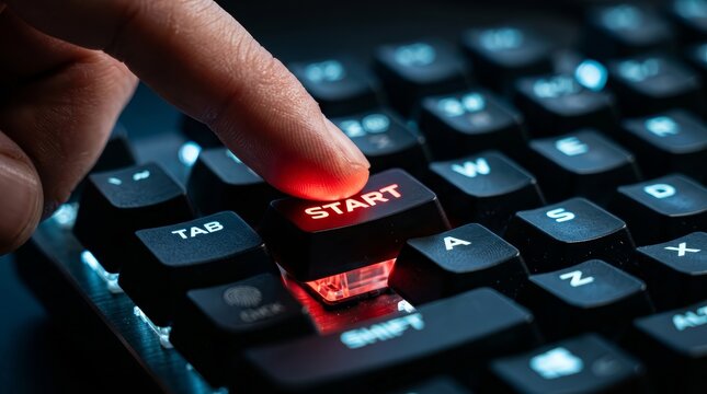 A human finger pressing the illuminated start button on a computer keyboard.