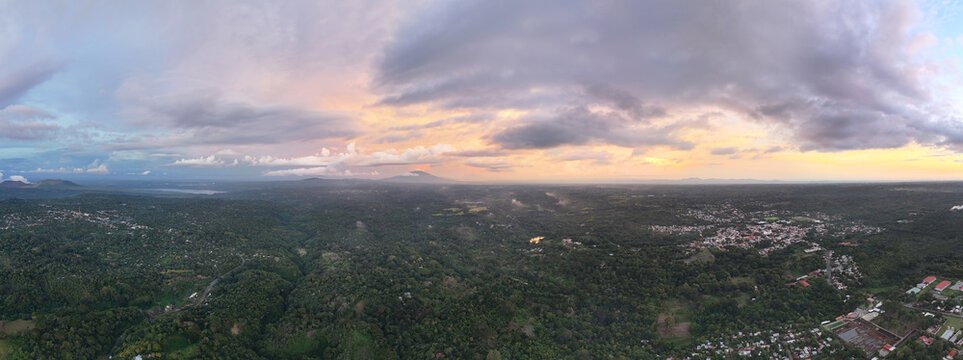 Aerial view of the lush green landscape with scattered houses and a dramatic sunset sky over the horizon in San Marcos, Carazo, Nicaragua.