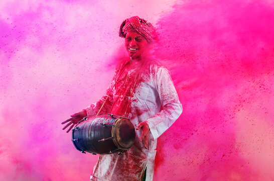 Young Indian man With Colored Face Dancing During Holi Color festival
