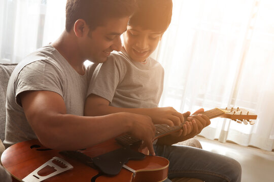 Father teaching guitar lessons to son 
