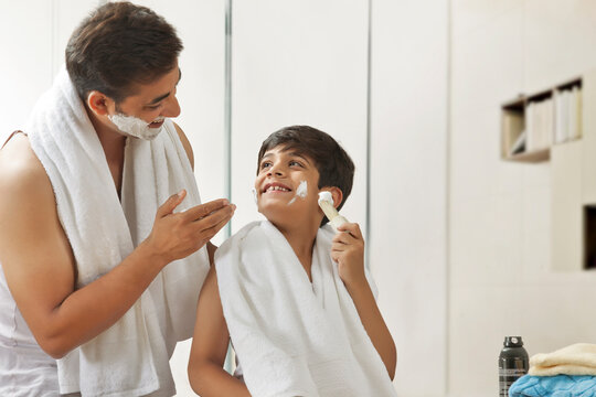 Boy applying shaving cream with father