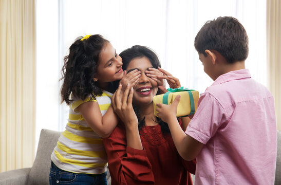 Two children presenting gift to their mother