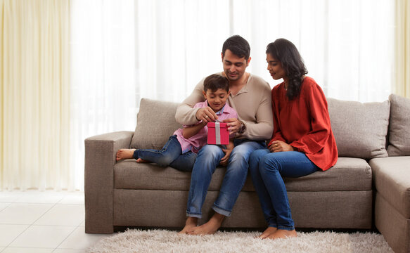 Smiling parents with son opening gift box
