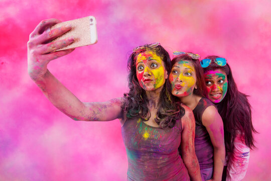 Three Indian teenage girls taking selfie during Holi Color festival
