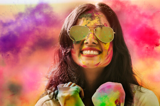 Portrait of a smiling girl with mirror sunglasses covered with colorful Gulal powder during a Holi festival