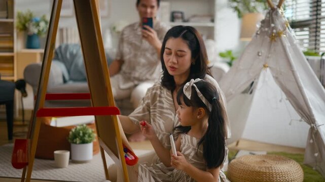 Asian mother or father teaching daughter doing homework on laptop at home. Parents supporting girl during summer break and back to school season.Concept of child education and family relationship life