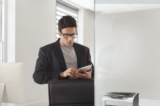 Businessman with eyeglasses using digital tablet in modern office