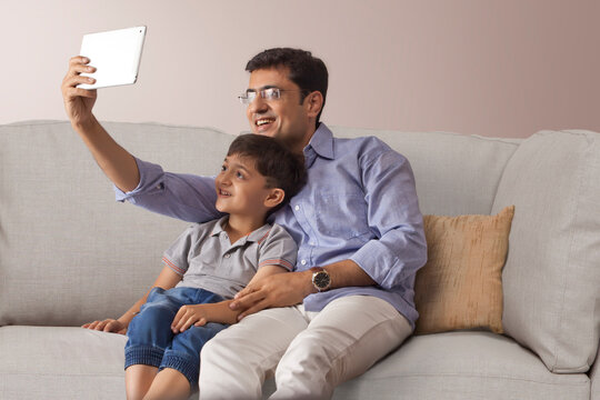 Happy father and son taking selfie with digital tablet