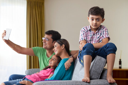 Conflicts with family,Portrait of serious boy with his parents and sister using digital tablet in the background