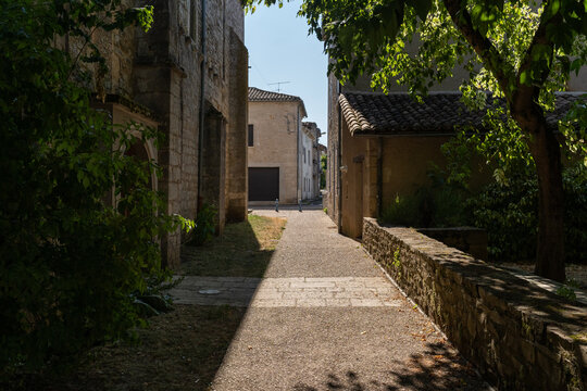 Shaded narrow cobblestone alleyway between historic stone houses in Septfonds village, Tarn-et-Garonne, France