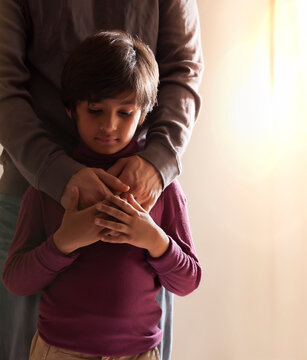 Boy holding his father hands standing together nearby the window 