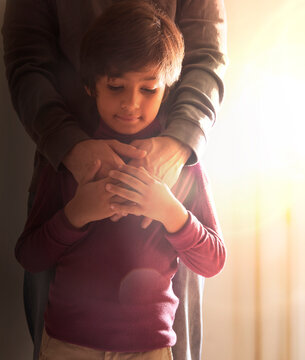 Boy holding his father hands standing together nearby the window 