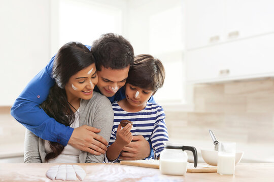 Parents and son baking cupcakes in kitchen