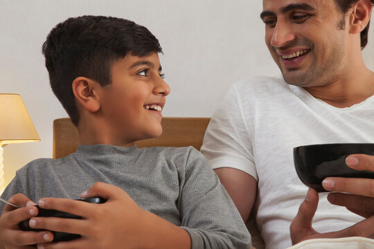 Close-up of father and son having breakfast in bed