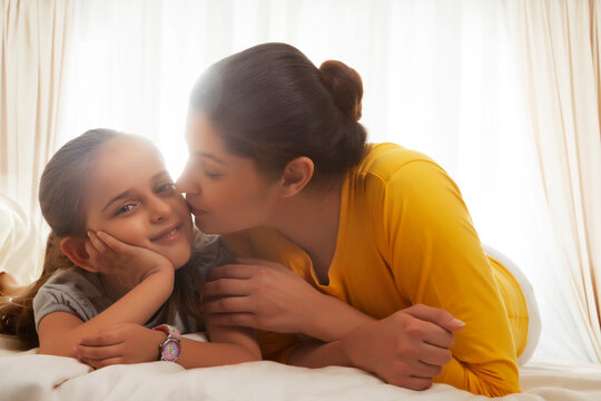 Affectionate mother with daughter in bed
