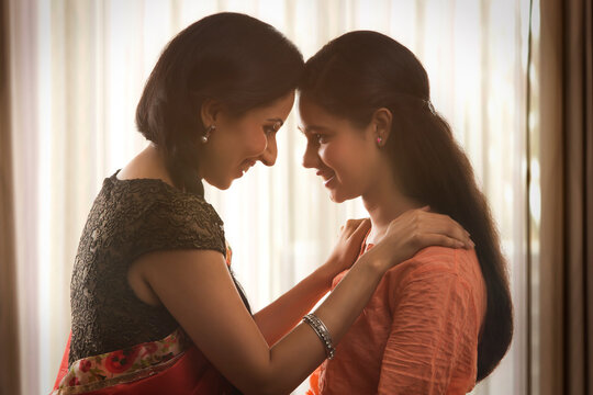 Smiling mother and daughter touching foreheads