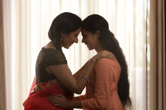 Smiling daughter and mother touching foreheads