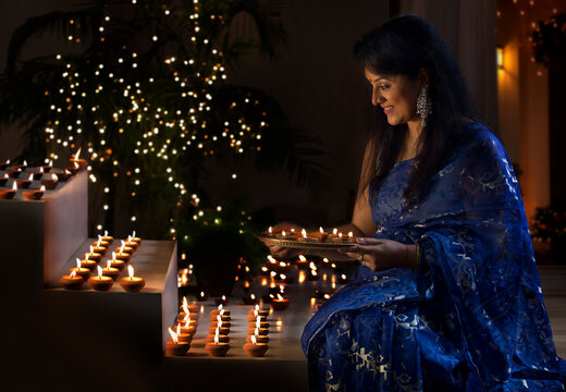 Woman arranging oil lamps on steps at a diwali festival