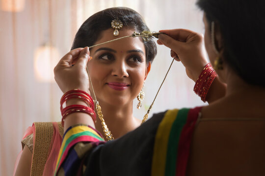 Rear view of mother placing necklace on daughter