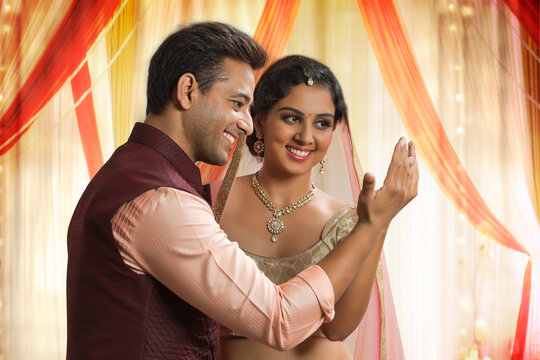 Beautiful young couple in traditional dress looking at their palms joined together