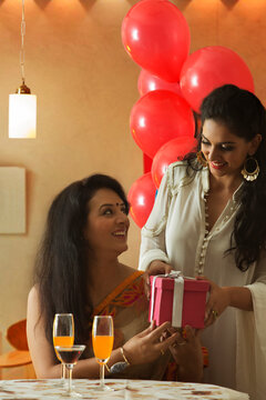Young daughter giving present to her mother at party