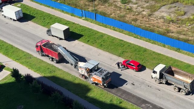 Traffic passes a highway construction zone with paving equipment nearby, transport safety, infrastructure maintenance, road engineering, aerial overview.