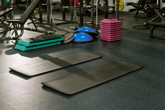 Empty fitness mats and workout equipment on gym floor, preparing for training session. Perfect for sports club marketing and fitness class promotion
