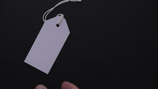 Numerous white paper price tags with strings falling onto a black background