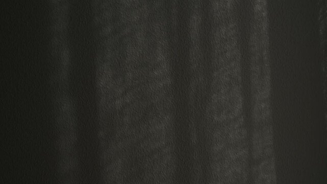 Macro shot of abstract shadow play moving across a dark gray textured wall