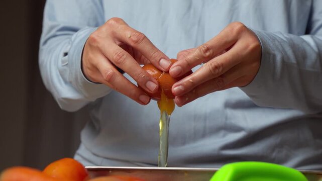 Person cracks open a fresh, bright orange egg
