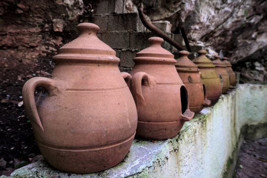 A row of handmade terracotta pots with lids on a stone ledge in Turkey. Traditional clay earthenware jars