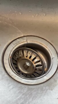 Stainless steel sink drain with visible crack in the basin